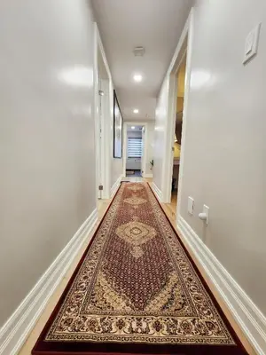 a hallway with a rug on the floor at The Serene Haven Modern 2 Queen Bed Full Apartment in St. Catharines
