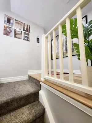 a staircase in a home with white walls and wooden railings at The Serene Haven Modern 2 Queen Bed Full Apartment in St. Catharines