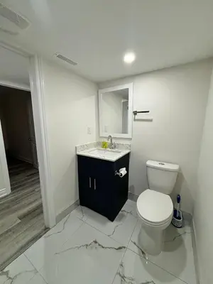 a white bathroom with a toilet and a sink at Bright Queen Room close to Sheridan College and Airport in Brampton