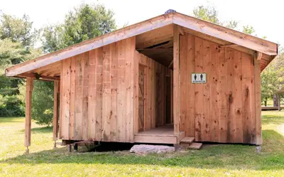 a wooden building with an open door in the grass at Homegrown Hideaway in Port Dover