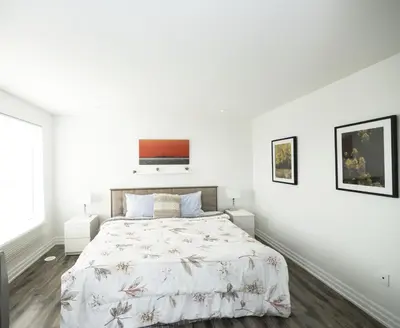 a white bedroom with a bed and two windows at Executive 3 Bedroom Town House in Mississauga