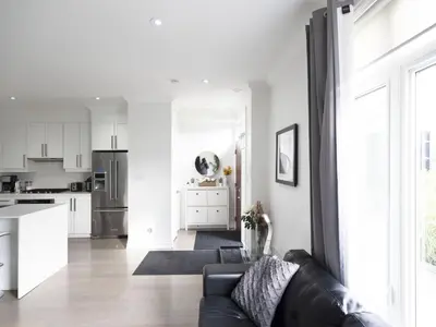 a living room with a black couch and a kitchen at Executive 3 Bedroom Town House in Mississauga