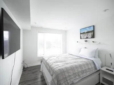 a white bedroom with a bed and a television at Executive 3 Bedroom Town House in Mississauga