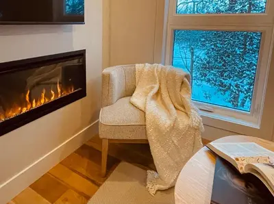 a living room with a chair and a fireplace at Elora’s Irvine River Suite in Elora