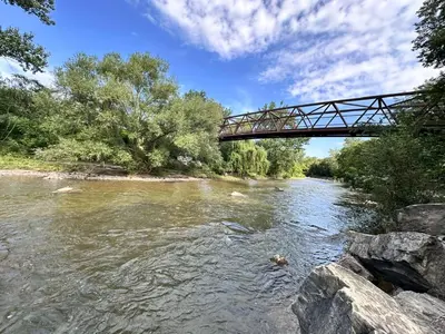a bridge over a river with rocks and trees at Riverwood Home in Mississauga