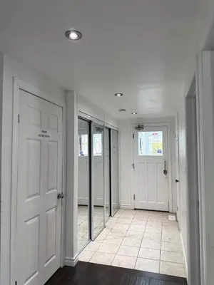 a hallway with white walls and doors and a tile floor at Riverwood Home in Mississauga