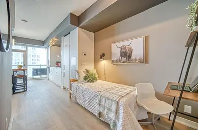a bedroom with a bed and a table and a chair at Skyline Retreat Residences in Toronto