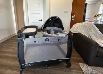 a baby crib sitting on the floor next to a couch at Golf Spa Relax in Collingwood