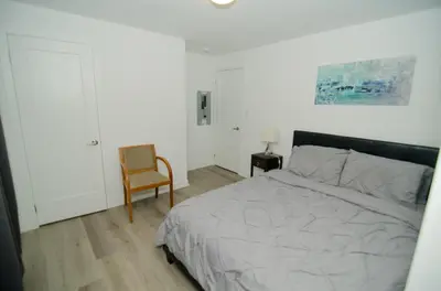 a bedroom with a large bed and a chair at Niagara Escape Crib: 3km from NiagaraFalls in Niagara Falls