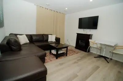 a living room with a couch and a table and a television at Niagara Escape Crib: 3km from NiagaraFalls in Niagara Falls