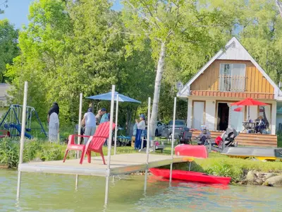 a dock with two chairs and an umbrella and a house at Charming Winter Cottage Retreat with Scenic Snow Views in Colborne