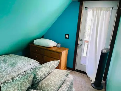 a bedroom with blue walls and a bed and a window at Charming Winter Cottage Retreat with Scenic Snow Views in Colborne
