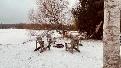 three benches sitting in the snow next to a lake at Charming Winter Cottage Retreat with Scenic Snow Views in Colborne