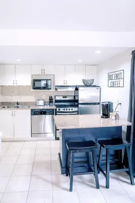 a kitchen with white cabinets and a blue island with stools at Gorgeous Studio Condo in Blue Mountains Sleeps 4 in Blue Mountains