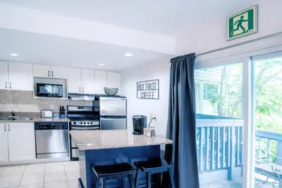 a kitchen with white cabinets and appliances and a balcony at Gorgeous Studio Condo in Blue Mountains Sleeps 4 in Blue Mountains