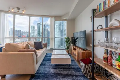 a living room with a couch and a large window at Toronto Views ~ Pool ~ BBQ ~ Harbourfront ~ WIFI in Toronto