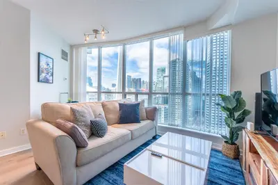 a living room with a couch and a large window at Toronto Views ~ Pool ~ BBQ ~ Harbourfront ~ WIFI in Toronto