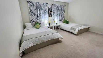 a bedroom with two beds and a table in it at Cozy Town house in Toronto