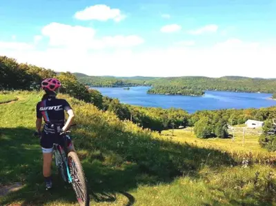 a person on a bike on a hill overlooking a lake at The Hidden Porch at Sir Sam's (hot tub & sauna) in Haliburton