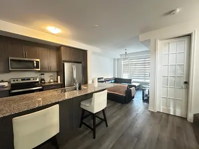 a kitchen with a counter top and a living room at Keppel Circle Residence in Brampton