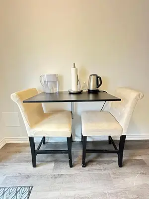 a black dining table with two chairs and a table with two pitchers at Keppel Circle Residence in Brampton
