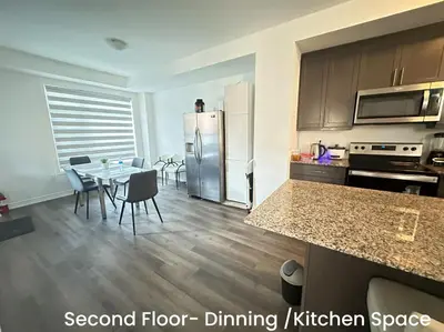 a kitchen and dining room with a table and refrigerator at Keppel Circle Residence in Brampton