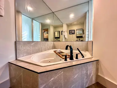 a bathroom with a bath tub with a large mirror at 40BKickBack in Collingwood