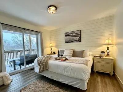 a bedroom with a large bed and a balcony at Beautiful tranquil centrally located condo in Collingwood