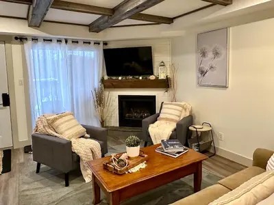 a living room with a table and a fireplace at Beautiful tranquil centrally located condo in Collingwood
