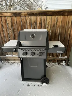 a grill sitting in the snow next to a fence at Spa Golf Bike in Collingwood