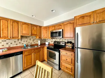 a kitchen with wooden cabinets and a stainless steel refrigerator at Spa Golf Bike in Collingwood