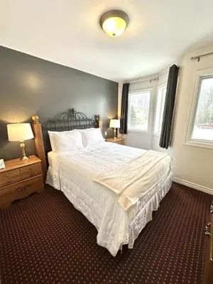 a bedroom with a large bed and two windows at 19th Hole Hideaway in Collingwood