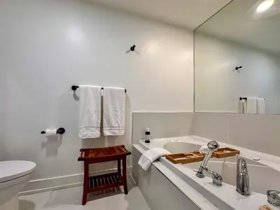 a bathroom with a tub and a toilet and a sink at The Fairway Flat in Collingwood