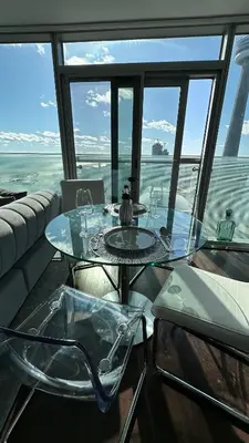 a glass table in a room with a view of the ocean at DOWNTOWN, LUXURY CONDO, CN TOWER, ROGERS CENTER, SCOCIA ARENA, UNOBSTRUCTED VIEW in Toronto