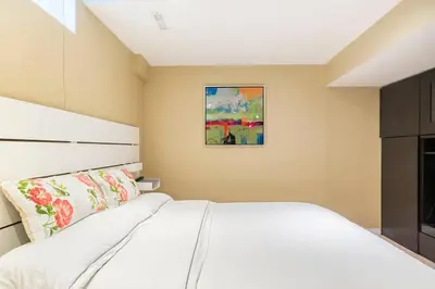 a bedroom with a white bed and a painting on the wall at Cozy basement apartment in Newmarket in Newmarket