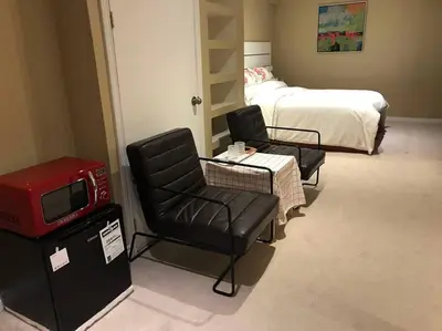 a room with two chairs and a bed and a tv at Cozy basement apartment in Newmarket in Newmarket
