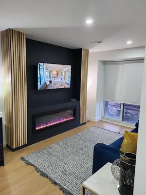 a living room with a fireplace and a tv on a wall at Exclusive Home in Niagara Falls in Thorold