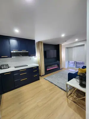 a kitchen with blue cabinets and a living room at Exclusive Home in Niagara Falls in Thorold