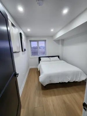 a white bedroom with a bed and a window at Exclusive Home in Niagara Falls in Thorold