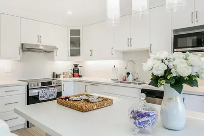 a white kitchen with a vase of flowers on a counter at Pristine Pet & Smoke Free 4-Bedroom home near Canada's Wonderland in Vaughan