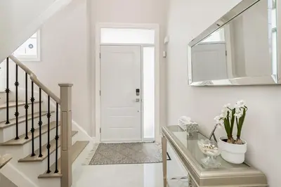 a hallway with a white door and a glass table with flowers at Pristine Pet & Smoke Free 4-Bedroom home near Canada's Wonderland in Vaughan