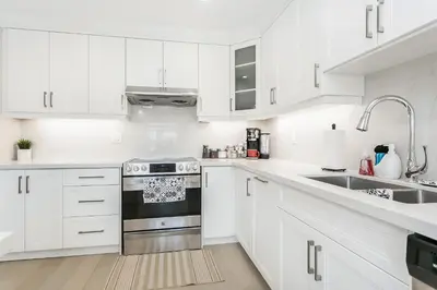 a white kitchen with white cabinets and a sink at Pristine Pet & Smoke Free 4-Bedroom home near Canada's Wonderland in Vaughan