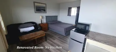 a small room with a bed and a refrigerator at Tay Motel in Waubaushene