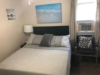 a bedroom with a bed and a chair and a window at Tay Motel in Waubaushene