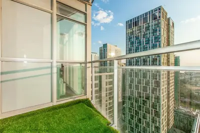 a balcony with green grass and large windows at SkyHigh Haven LED-Lit Downtown Condo Retreat in Toronto