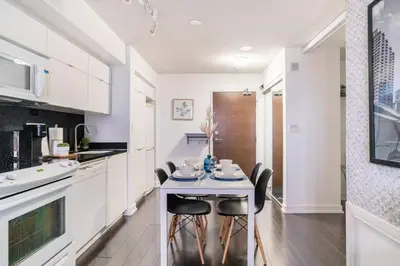 a white kitchen with a table and chairs at SkyHigh Haven LED-Lit Downtown Condo Retreat in Toronto