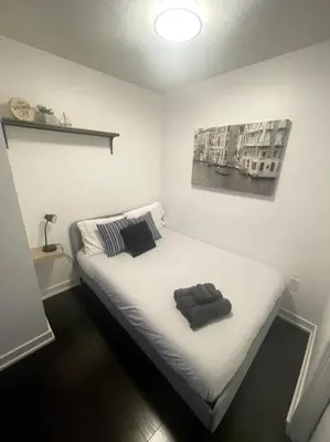 a bedroom with a white bed with a picture on the wall at SkyHigh Haven LED-Lit Downtown Condo Retreat in Toronto