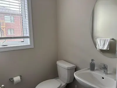 a bathroom with a toilet and a sink and a mirror at Beautiful New Townhouse in Quiet Neighbourhood in Ajax