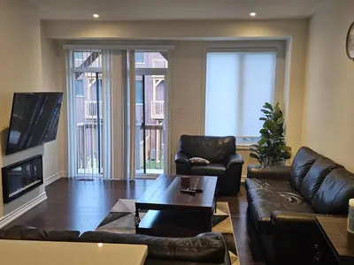 a living room with a leather couch and a table at Beautiful New Townhouse in Quiet Neighbourhood in Ajax