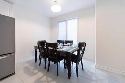 a dining room with a table and black chairs at Beautiful New Townhouse in Quiet Neighbourhood in Ajax